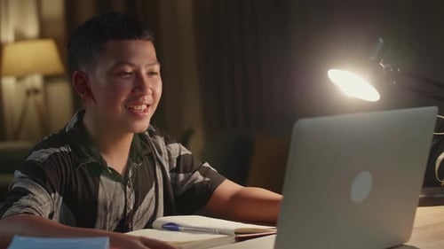 Teen Using Laptop for Online Video Call at Night