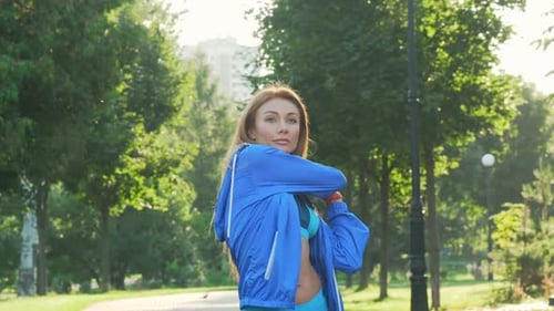 Beautiful Sportswoman Warming Up Before Jogging in the Park