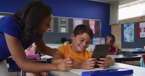 Teacher Helping Student with Tablet in Classroom