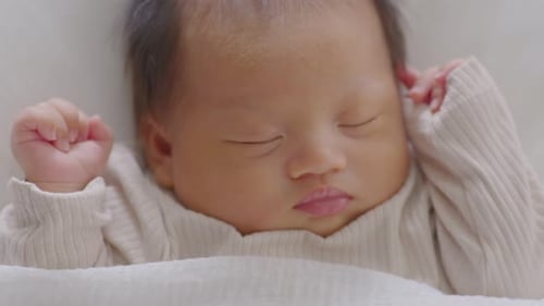 Close up happy newborn baby lying sleeps on a white blanket comfortable and safety