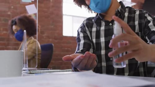 Young Adult Applies Hand Sanitizer at Office Desk