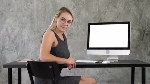 Woman Smiling at Desk in Front of Computer