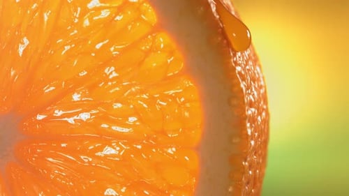 Une goutte d'eau coule à la surface d'une tranche d'orange mûre et juteuse