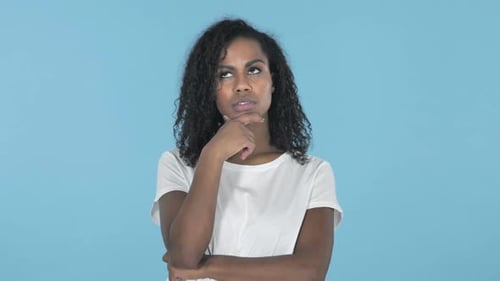 Das denkende afrikanische Mädchen hat eine neue Idee isoliert auf blauem Hintergrund bekommen