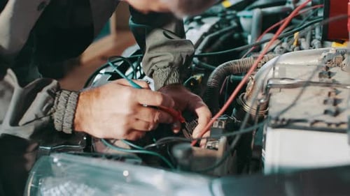 Adult Repairs Car Engine with Electrical Test Equipment
