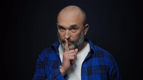 A Bearded Man Puts His Finger To His Lips Asking for Silence Closeup