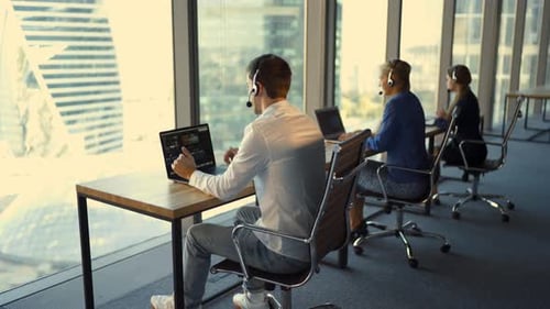 Rückansicht einer gutaussehenden jungen Geschäftsfrau und schöner Geschäftsfrauen in Headsets, die im Büro arbeiten