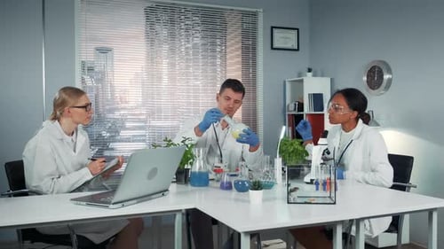 Vielfältiges Forscherteam beobachtet das Experiment des Kollegen mit Flüssigkeit in einem konischen Kolben