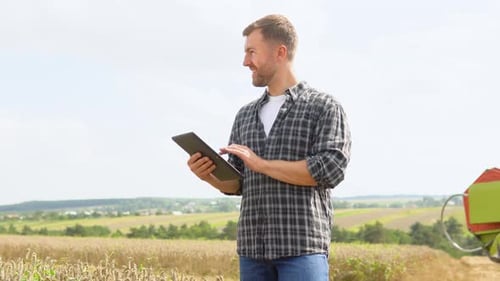 Farmer in Wheat Field Holding Digital Tablet