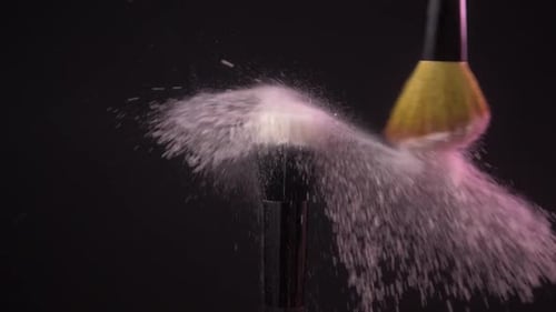 Dos Pinceles de maquillaje con polvo sobre un fondo oscuro