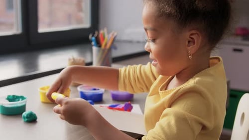 Little Girl Playing with Modeling Clay at Home
