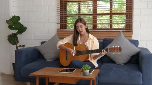 Young Woman Plays Guitar at Home