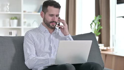 Man Talking on Phone While Using Laptop