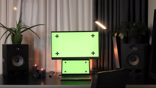 Office desk with laptop computer mock-up green screen displays.