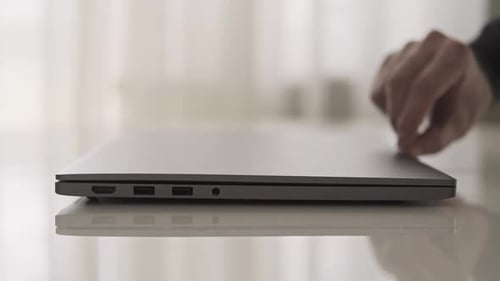 Hand Opens Sleek Modern Laptop on Glass Table