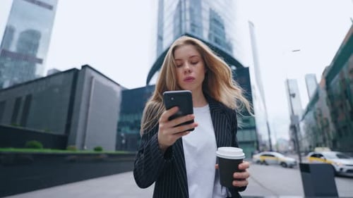A Confident Corporate Office Woman Employee in Formal Dress Holding a Coffee Mug and Phone in Hands
