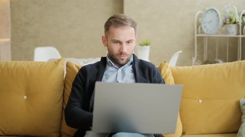 Man Working on Laptop at Home on Couch