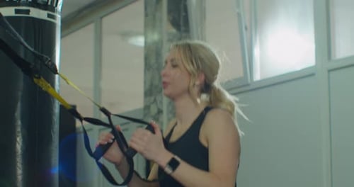 Woman Working Out with TRX Straps in Gym