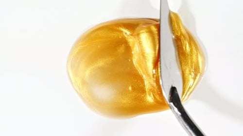 Gold Cosmetic Product Being Smeared with a Spatula