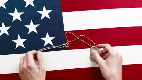 Hands Place Military Dog Tag on American Flag