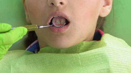 Dentist Examining Child's Teeth With Mirror Tool
