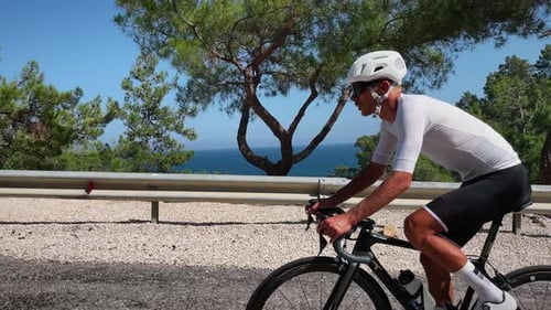 Man riding bicycle. Cyclist riding sports bicycle uphill. Triathlete riding racing bicycle