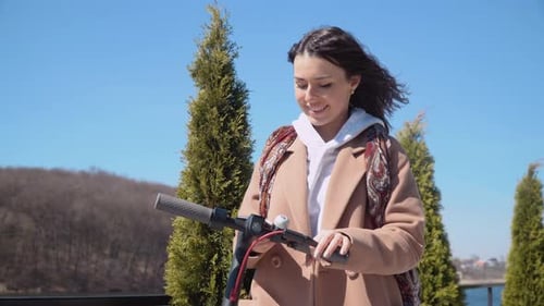Young Woman Using Smartphone with Electric Scooter Outdoors