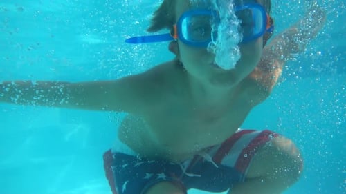 Underwater shot of a boy playing in a pool at a hotel resort.
