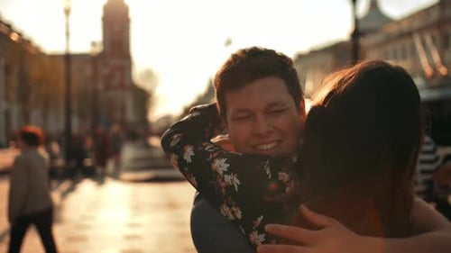 A Man Meets a Woman Walking Down the Street and Gives Her a Hug, Close Up