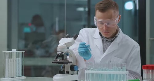 Scientist Works with Microscope in Clean Lab