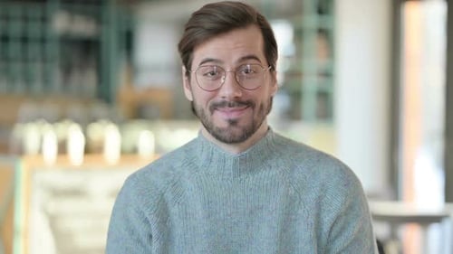 Man Gives OK Sign with Blurred Workplace Background