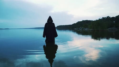 Scary Figure in Black Mantle in the River