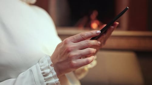 Woman in White Reading Interesting Ebook Reader While Sitting Near Fireplace at Home