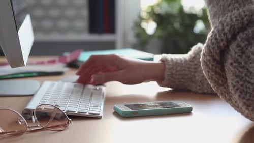 Junge Frau scrollt und schreibt SMS mit ihrem Smartphone und Computer
