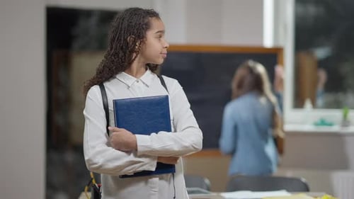 Smiling Student Holding Book in a Classroom