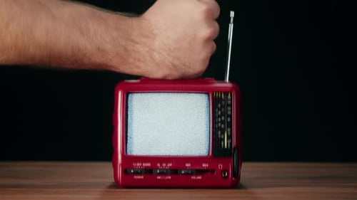 Knocking on Small Old Television with Grey Interference Screen on Black Background