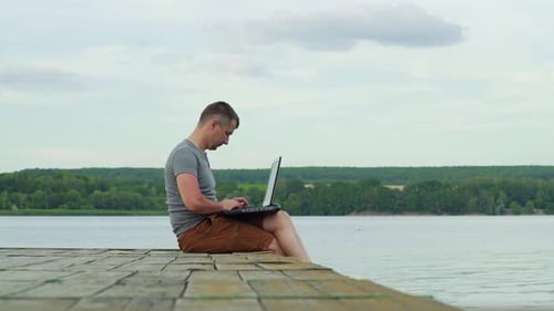 Man on the Pier Working on a Laptop