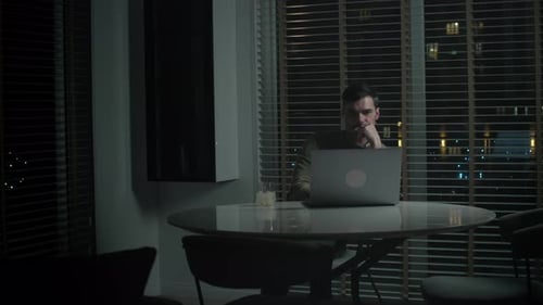 Man Works Late at Laptop in Urban Apartment