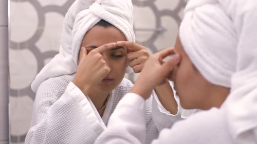 Frau drückt Pickel im Badezimmer