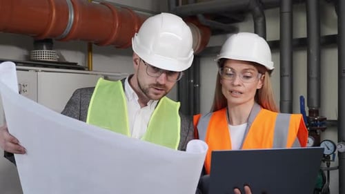 Engineer Planning Work Builders Using Blueprints and Laptop