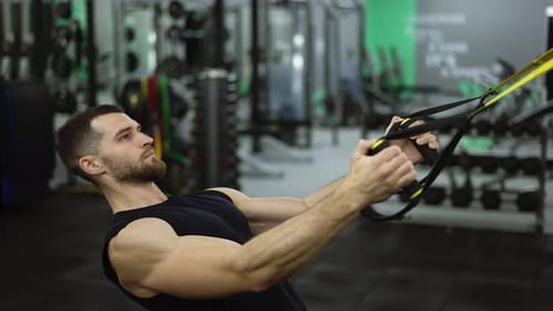 Seitenansicht eines starken Sportlers, der im Fitnessstudio Übungen mit TRX-Gurten macht