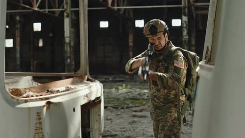 Camouflage Soldier Aims Weapon in Warehouse Ruins