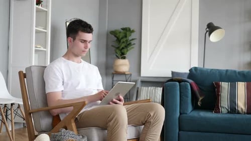 Young Man Using Tablet Device While Sitting Indoors