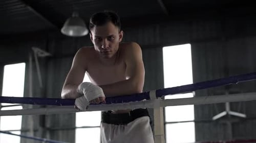 Boxer Leans Against Ropes in Boxing Ring