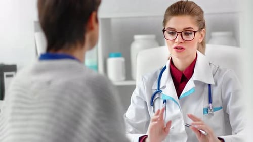 Young Woman Doctor Talking to Patient in Office