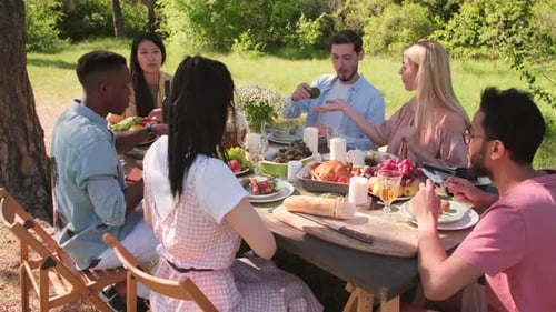 Friends Enjoying Food at Sunny Outdoor Picnic