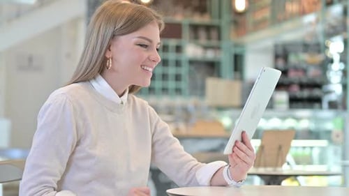 Video Chat on Tablet By Young Woman in Cafe