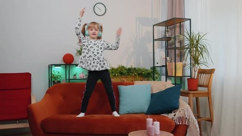 Happy Child Dancing to Music on Sofa