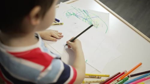 Young Child Drawing with Crayons at Table
