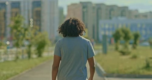 Man with Long Hair Walks Along the City Street a Walk in the Summer